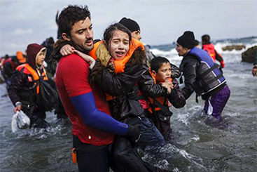 A volunteer life-guard helps a young girl out of the sea